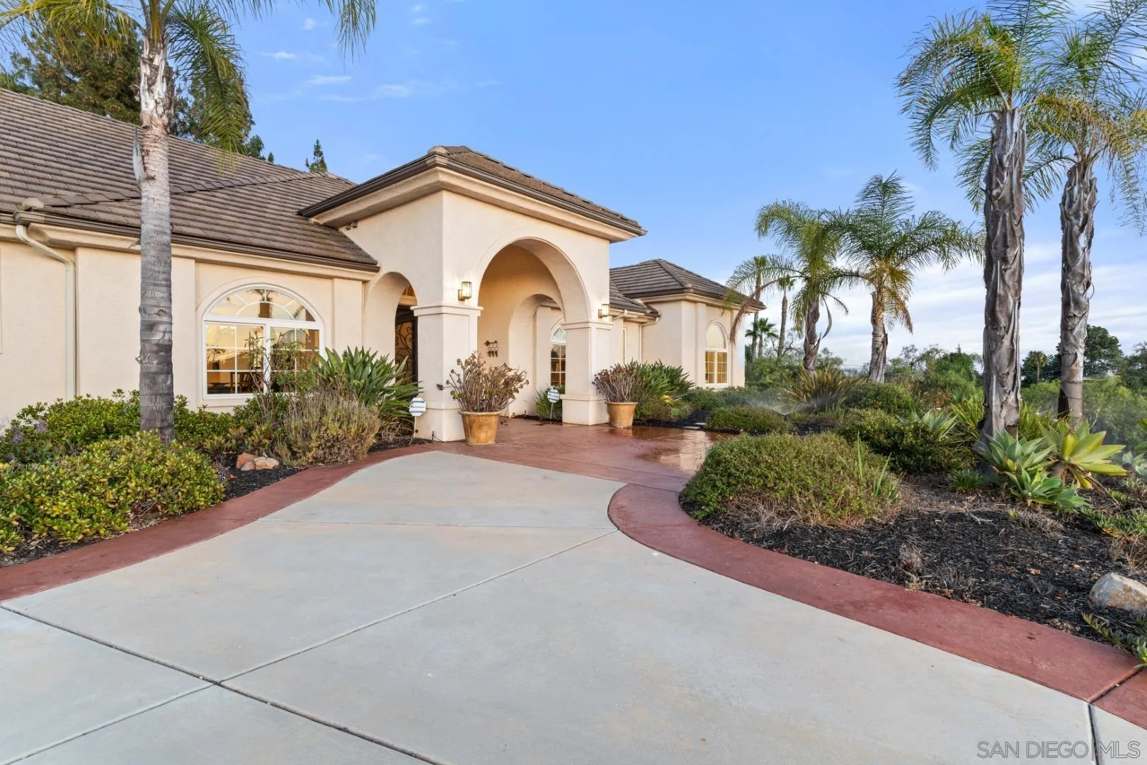 246 Yucca Road Fallbrook, CA 92028 - Photo 4 of 68 a view of a white house with a large windows and flower plants