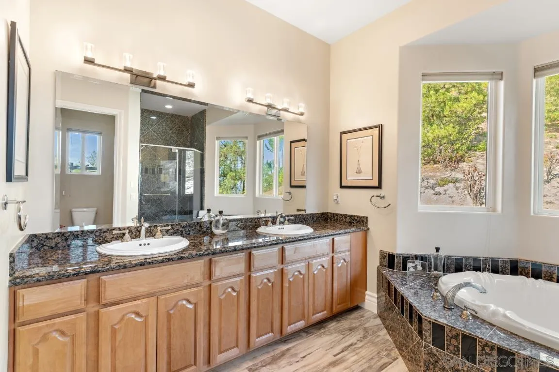 246 Yucca Road Fallbrook, CA 92028 - Photo 42 of 68 a bathroom with a granite countertop tub a double vanity sink and a large mirror