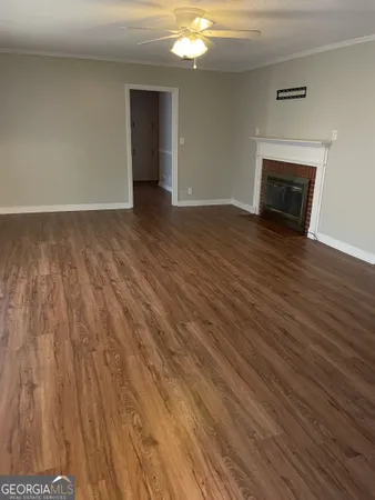 a view of an empty room with wooden floor and a fireplace