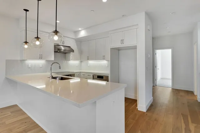 a large kitchen with stainless steel appliances a large counter top and a refrigerator