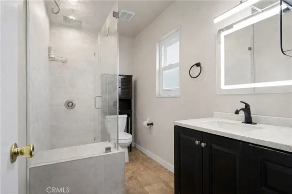 a bathroom with a tub sink vanity granite and shower