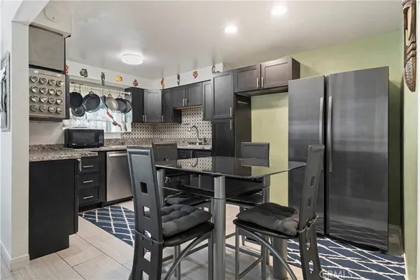 a kitchen with stainless steel appliances a refrigerator a sink a stove a table and chairs