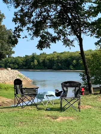 a view of a lake with table and chairs potted plants and large tree