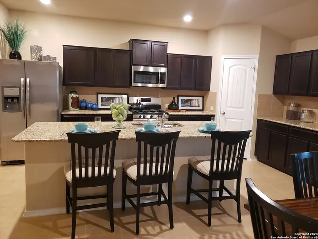a kitchen with stainless steel appliances a table chairs microwave and refrigerator