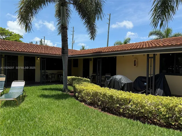 front view of house with a yard and potted plants