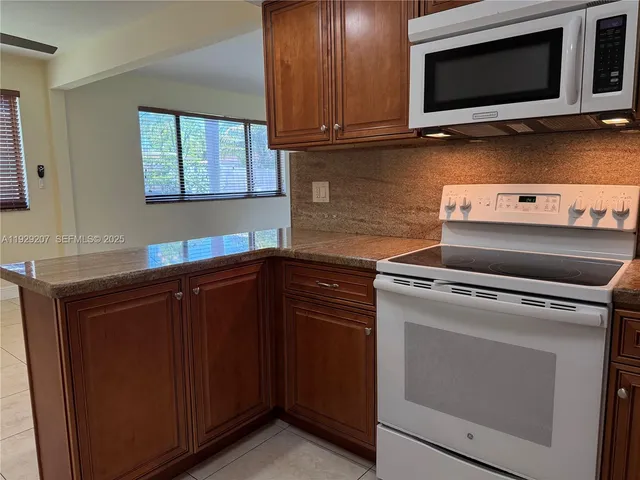 a kitchen with granite countertop cabinets appliances and wooden floor