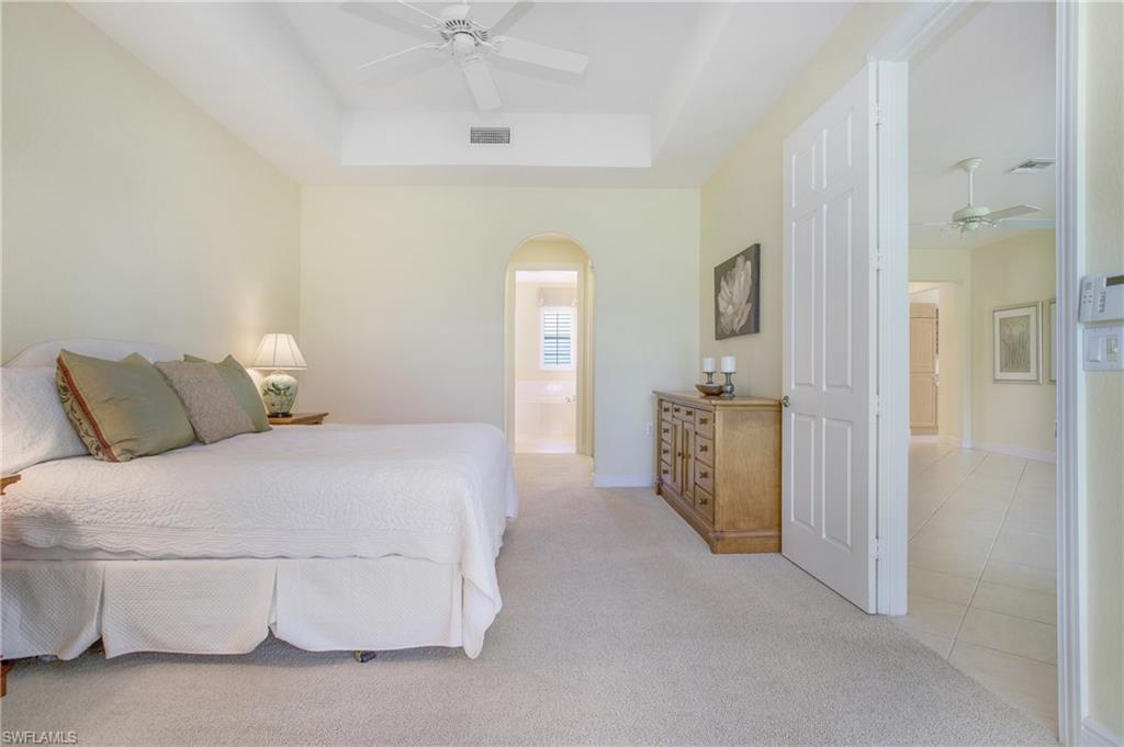 758 Regency Reserve Circle, Unit 2103 Naples, FL 34119 - Photo 26 of 41 a spacious bedroom with a bed and a chandelier