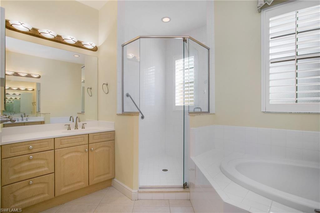 758 Regency Reserve Circle, Unit 2103 Naples, FL 34119 - Photo 29 of 41 a bathroom with a bathtub a double vanity sink and mirror