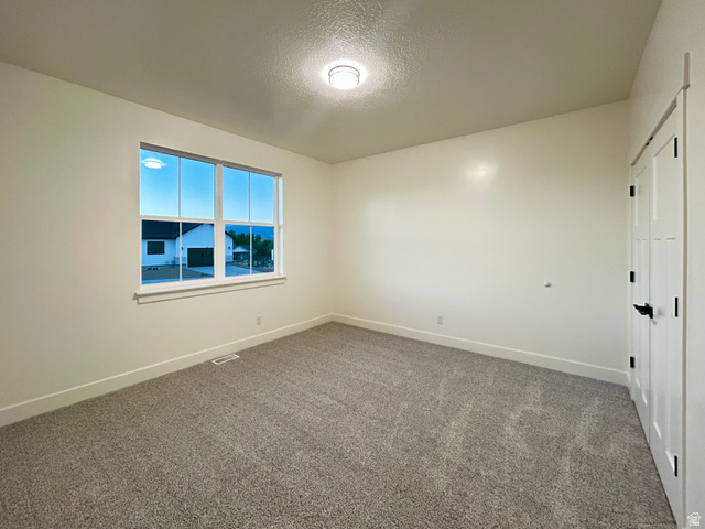 6 South 450th West Gunnison, UT 84634 - Photo 15 of 45 Bright room featuring a large window, neutral wall paint, gray carpet, white trim, and a white interior door with black hardware