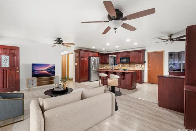 a living room with furniture kitchen view and a wooden floor