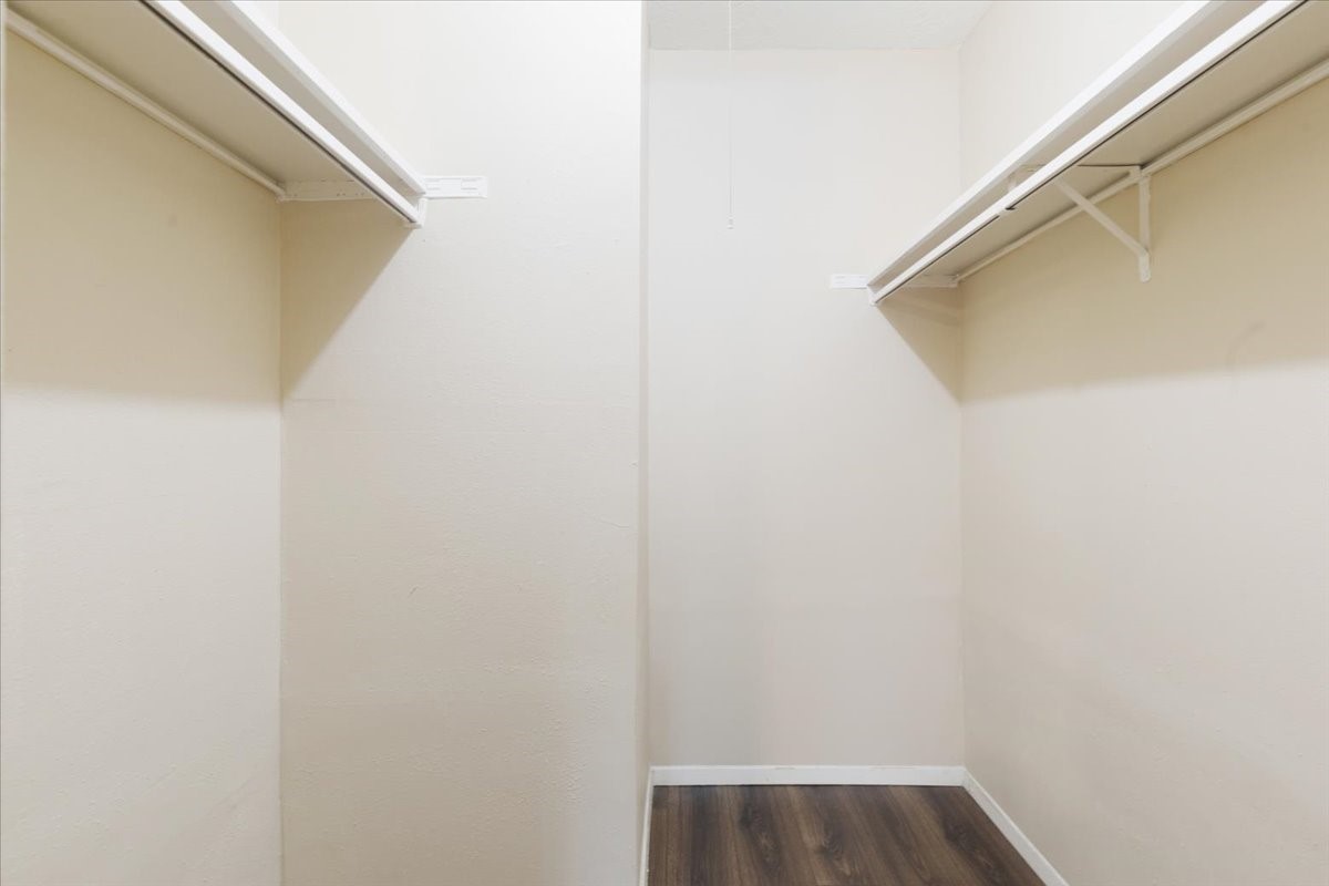 3502 Ocee Street, Unit 3502 Houston, TX 77063 - Photo 13 of 28 This photo shows a spacious walk-in closet with light-colored walls and wood flooring. It features two long shelves on either side for ample storage.