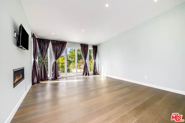 a view of an empty room with wooden floor and a fireplace