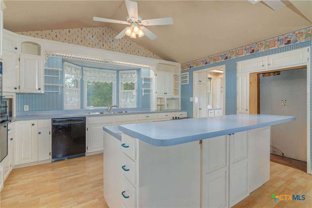 2981 Vivroux Ranch Road Seguin, TX 78155 - Photo 11 of 43 a kitchen with a sink dishwasher a stove and white cabinets with wooden floor