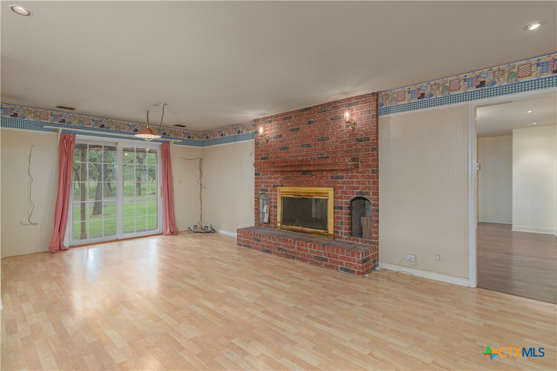 2981 Vivroux Ranch Road Seguin, TX 78155 - Photo 16 of 43 an empty room with wooden floor fireplace and windows