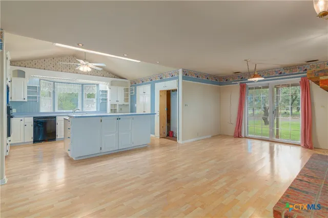 a kitchen with a sink dishwasher a stove and white cabinets with wooden floor