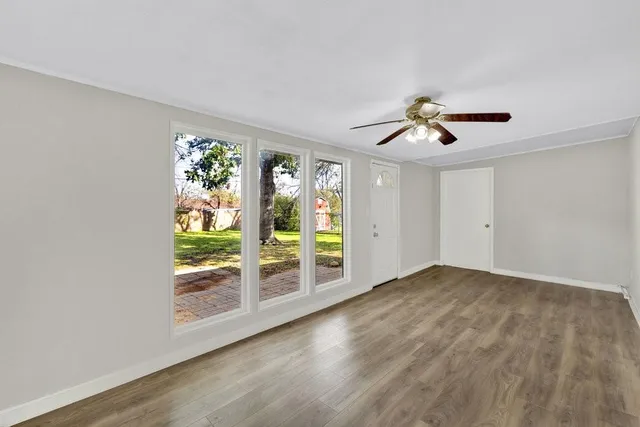 an empty room with windows and chandelier fan