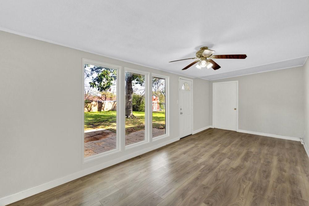 6833 Norma Street Fort Worth, TX 76112 - Photo 4 of 17 an empty room with windows and chandelier fan