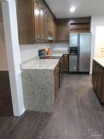 a kitchen with granite countertop a refrigerator and a sink