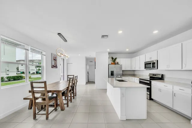 a kitchen with stainless steel appliances kitchen island granite countertop a table chairs microwave and cabinets
