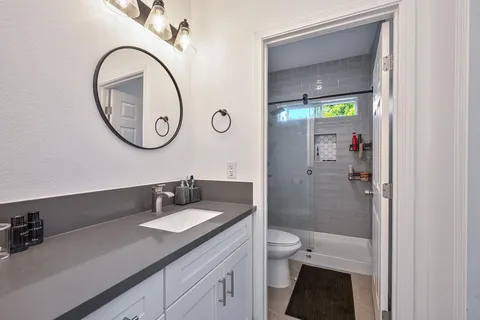 a bathroom with a granite countertop sink a toilet and a mirror