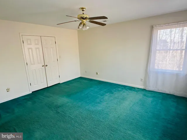 an empty room with a window and a fan