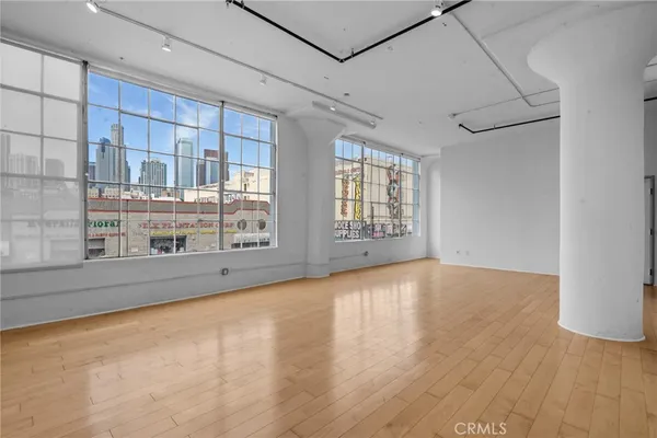 a view of an empty room with a window and wooden floor