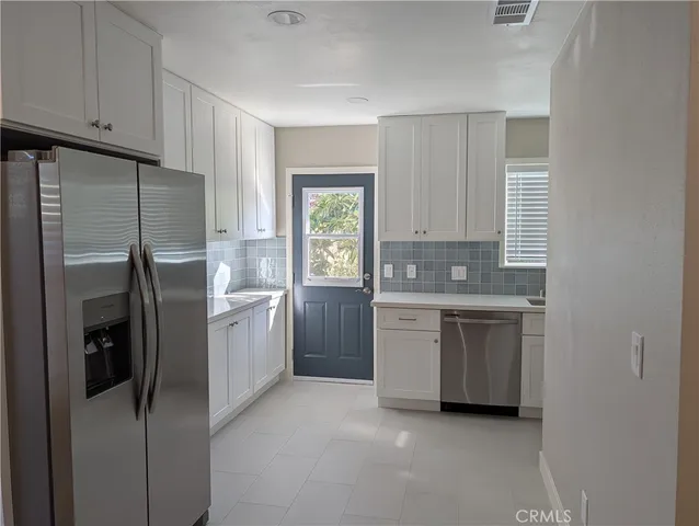 a kitchen with stainless steel appliances white cabinets and a refrigerator