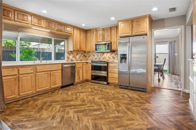 a large kitchen with stainless steel appliances granite countertop a refrigerator and a stove top oven