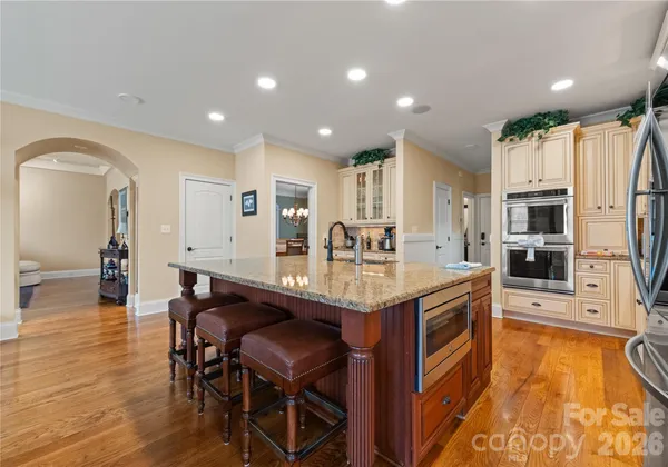 a kitchen with stainless steel appliances granite countertop a table chairs sink and cabinets