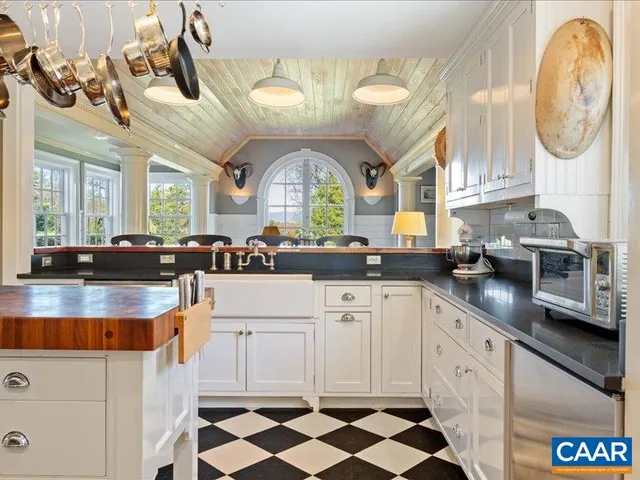 a large white kitchen with a large window a sink and cabinets