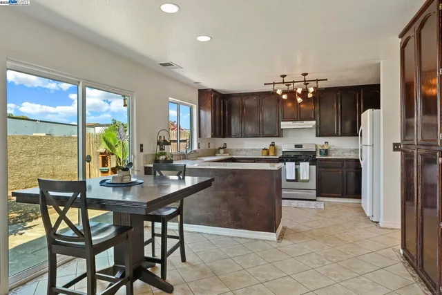 a kitchen with stainless steel appliances kitchen island granite top and refrigerator