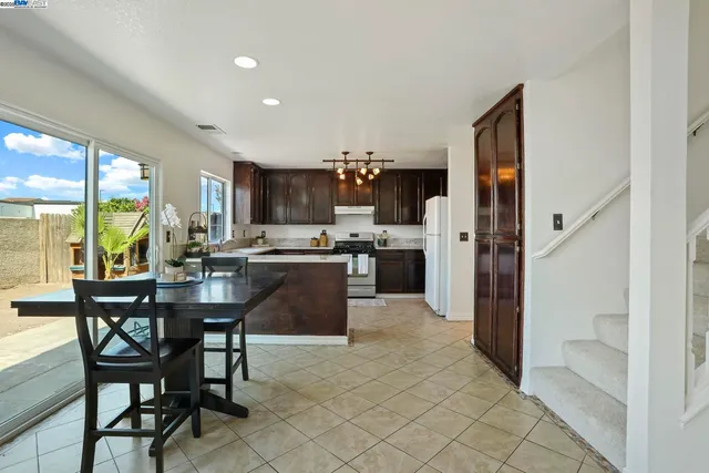 a kitchen with stainless steel appliances a dining table chairs and granite counter tops