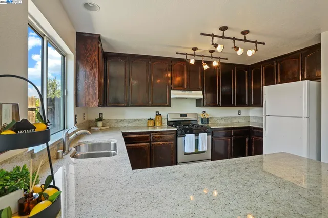 a kitchen with stainless steel appliances granite countertop a refrigerator stove sink and cabinets