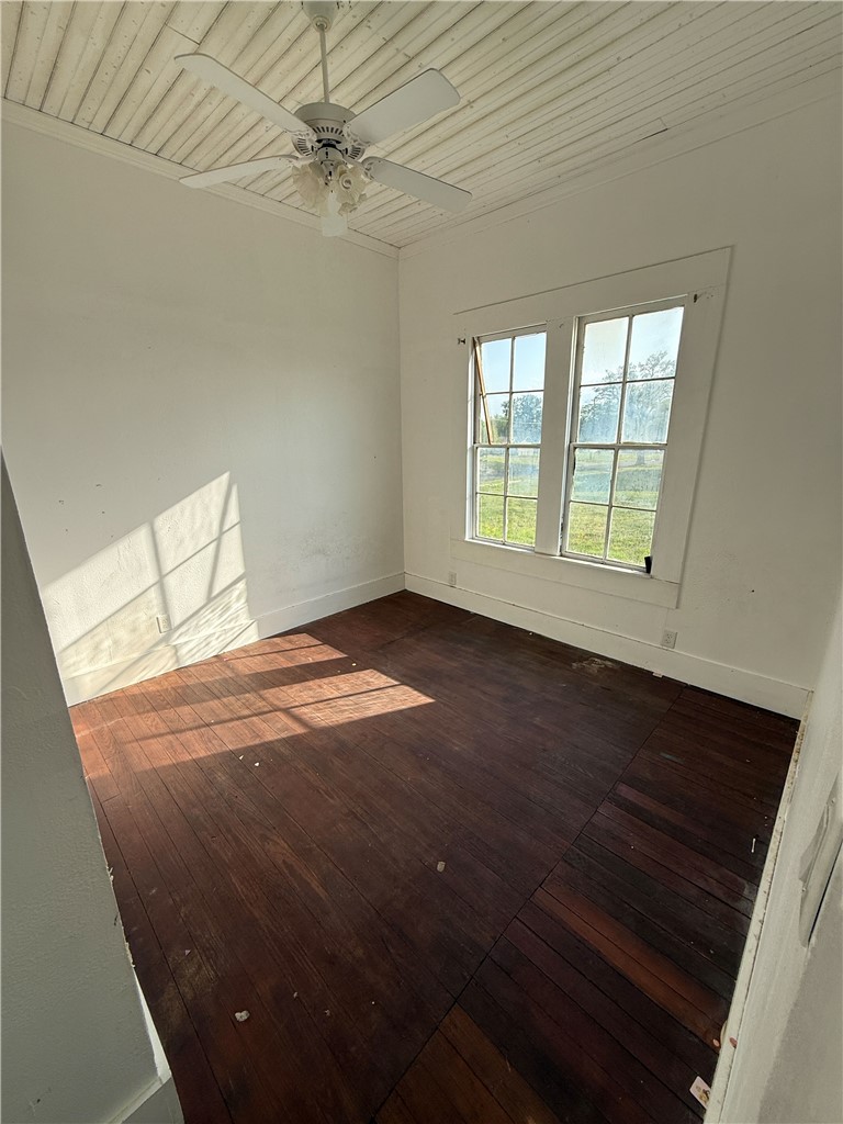 507 Logan Street Calvert, TX 77837 - Photo 11 of 19 Empty room featuring wooden ceiling, dark wood-style flooring, and ceiling fan