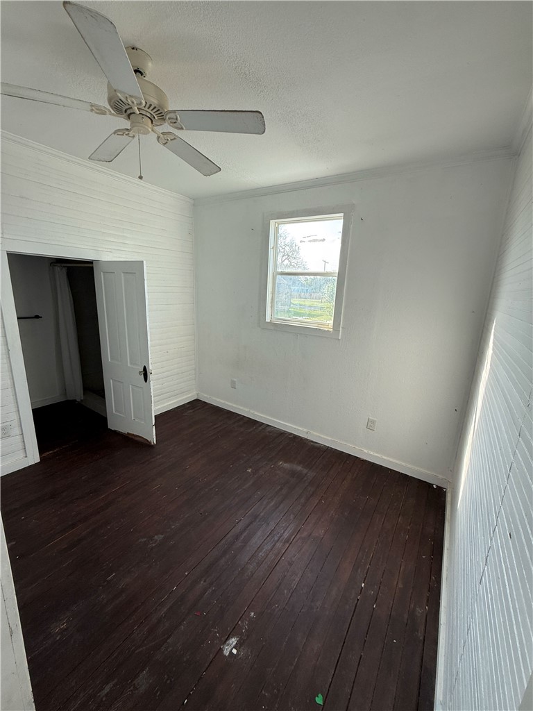 507 Logan Street Calvert, TX 77837 - Photo 12 of 19 Unfurnished bedroom featuring a ceiling fan, dark wood-type flooring, and a textured ceiling
