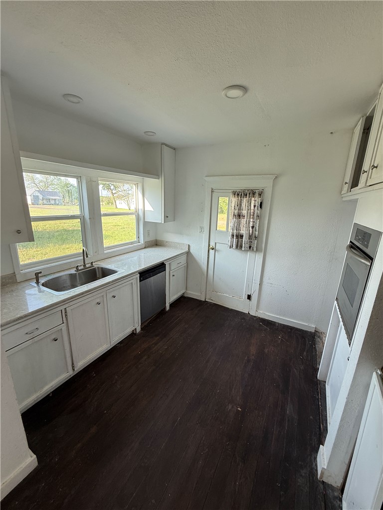 507 Logan Street Calvert, TX 77837 - Photo 9 of 19 Kitchen with white cabinetry, dark wood-type flooring, stainless steel appliances, and a textured ceiling