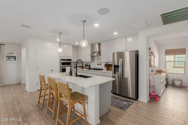 a kitchen with stainless steel appliances a refrigerator a stove a sink dishwasher and a dining table with wooden floor