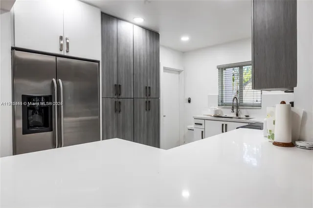 a kitchen with stainless steel appliances kitchen island granite countertop a refrigerator and a sink