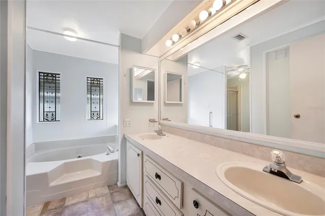 a bathroom with a tub a sink double vanity and mirrors