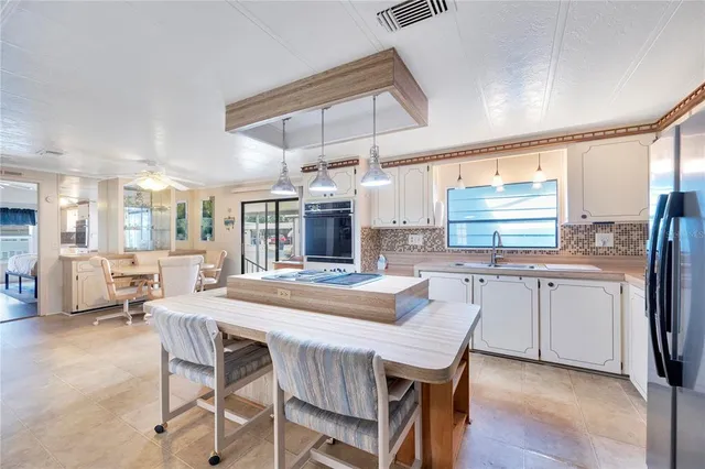 a dining room with stainless steel appliances kitchen island granite countertop a dining table chairs and granite counter tops