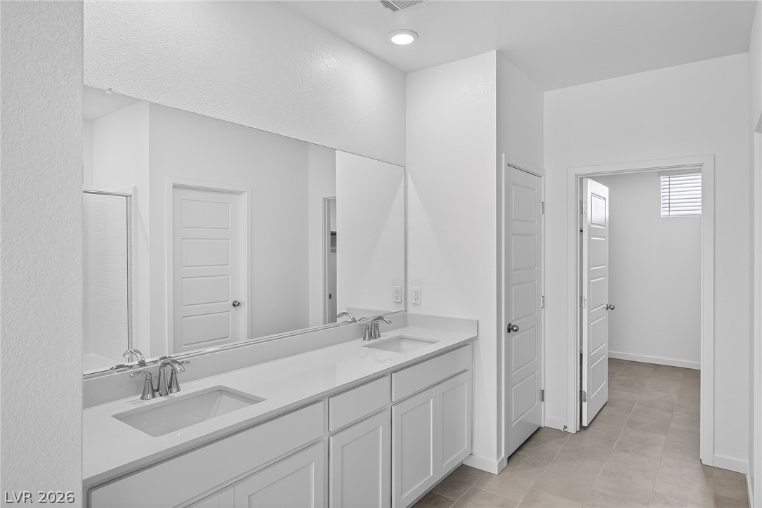 347 Sam Way Mesquite, NV 89027 - Photo 20 of 32 A well-appointed primary bathroom featuring a double vanity, large mirror, and ample cabinet storage.
