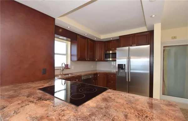 a kitchen with stainless steel appliances granite countertop a refrigerator a sink a stove a microwave and island