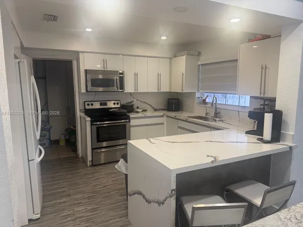 a kitchen with a sink a counter top space stainless steel appliances and cabinets