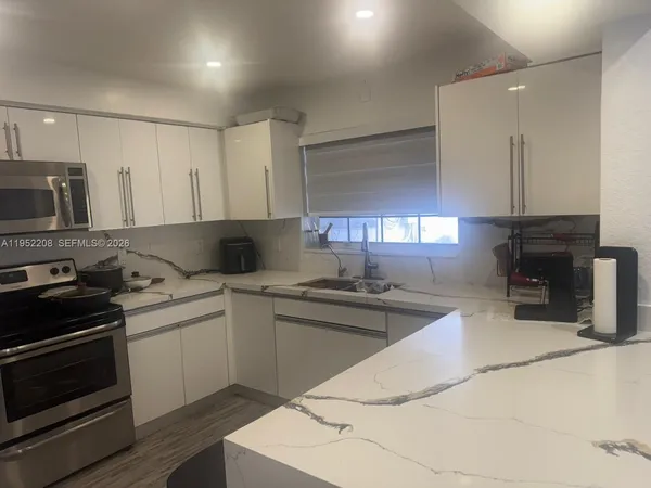 a kitchen with granite countertop a sink and stainless steel appliances