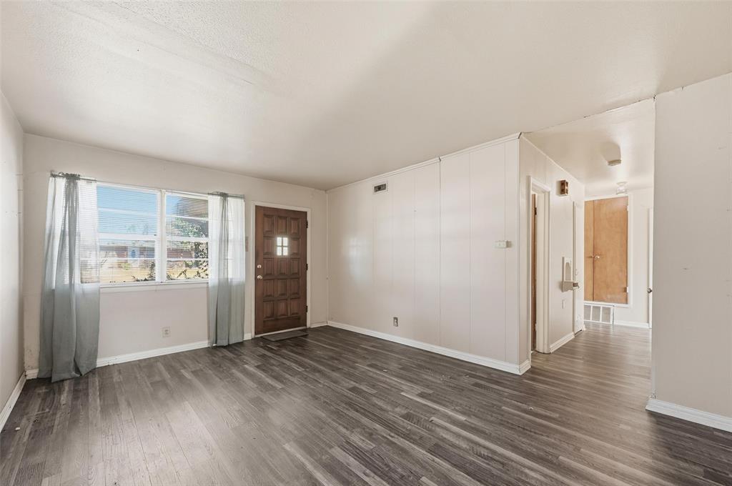 206 West Ridgewood Drive Garland, TX 75041 - Photo 6 of 21 a view of an empty room with wooden floor and a window