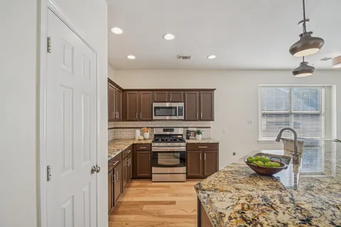 a kitchen with stainless steel appliances granite countertop a stove a sink and a refrigerator with wooden floor