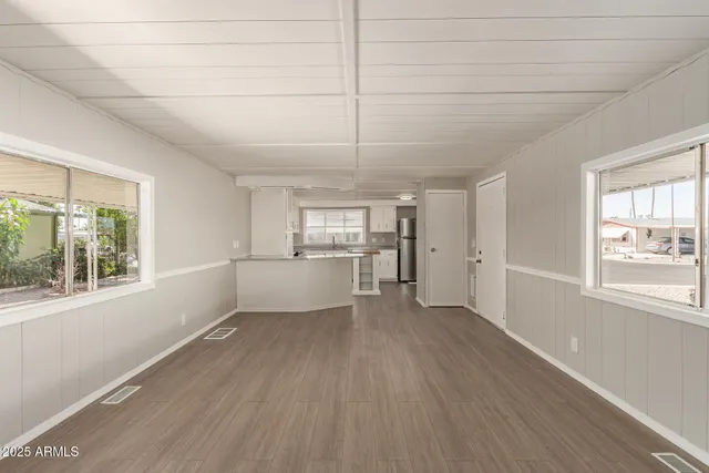 a view of a kitchen and an empty room with wooden floor and a window