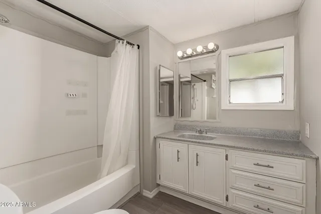 a bathroom with a granite countertop sink a mirror a shower and a bathtub