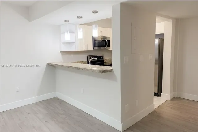 a view of a kitchen from the hallway with wooden floor