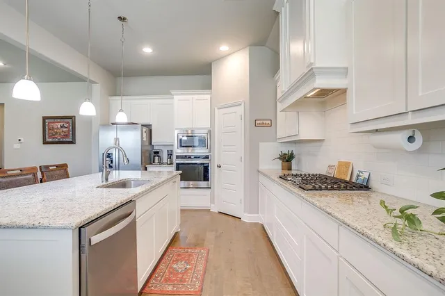 a kitchen with stainless steel appliances granite countertop a sink stove and refrigerator